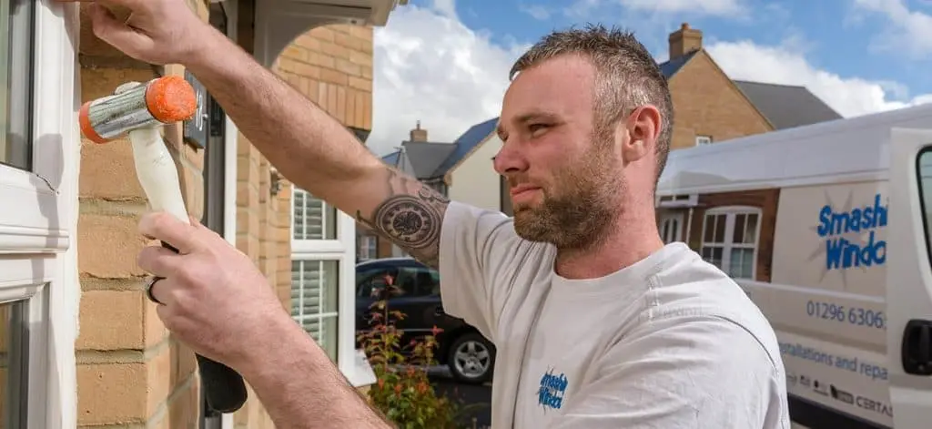 A Smashing Windows fitter sealing a window frame, with the company van behind him